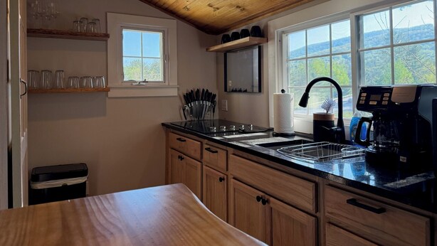 Una cocina con armarios de madera, una encimera negra, un fregadero, una cafetera y una ventana con vistas.