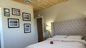 Un dormitorio con una cama grande, techo de madera y cuadros enmarcados en la pared.