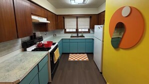 Una cocina con armarios de madera, estufa, pileta y refrigerador.