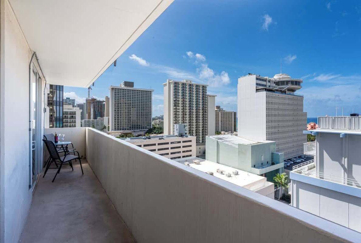 A balcony with a view of high-rise buildings and a clear sky.