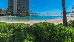 A beach resort with a large pool, palm trees, and a tall hotel building. - Marina Front, Large Lanai, Near Beach (Honolulu)