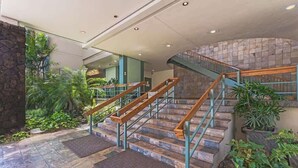 A staircase with wooden handrails and stone steps, surrounded by greenery and potted plants. - Marina Front, Large Lanai, Near Beach (Honolulu)