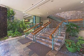 A staircase with wooden handrails and stone steps, surrounded by greenery and potted plants. - Marina Front, Large Lanai, Near Beach (Honolulu)