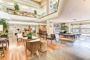 A spacious lobby with a high ceiling, a central seating area, and large windows. - Bright Central Studio at Luana Hotel + Suites (Honolulu)