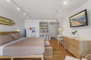 Ein modernes Schlafzimmer mit einem großen Bett, einem Schreibtisch und einem Fernseher.