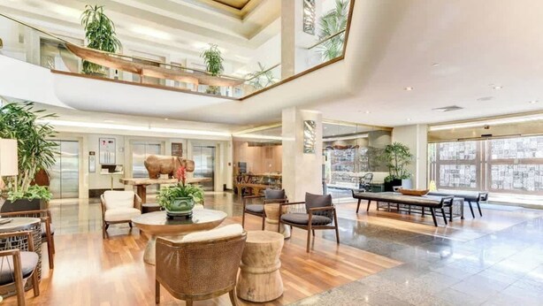 A spacious lobby with a high ceiling, multiple seating areas, and large windows offering views of the outside. - Cozy Waikiki Studio, Pool, Gym & BBQ (Honolulu)