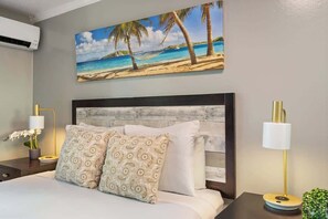 Ein Hotelzimmer mit einem Bett, einem Strandbild und zwei Nachttischlampen.