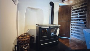 Una habitación con un estufa de leña de madera oscura, cestas de mimbre y una puerta de madera.