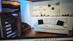 Una sala de estar con un sofá, una escalera de madera y una pared de piedra decorada.