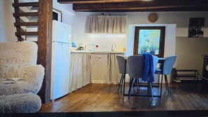 Una cocina funcional con comedor, piso de madera y vistas por la ventana.