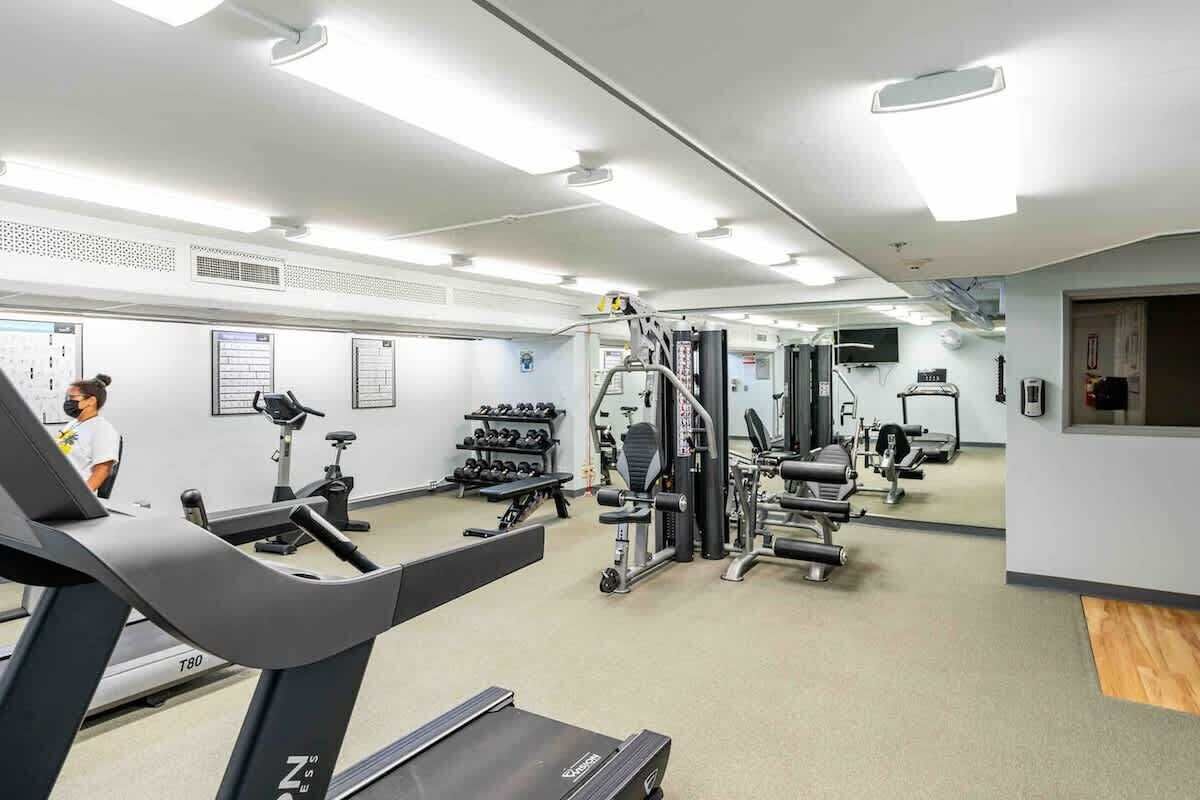 Une salle de sport équipée de tapis de course, d’appareils de musculation et d’haltères.