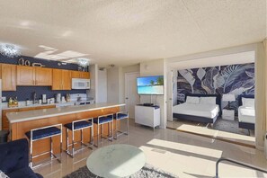 A modern hotel room with a kitchen, a dining area, a living room with a sofa and a TV, and a bedroom with a bed and a nightstand. - Stunning Diamond Head & Ocean Views, Free Parking (Honolulu)