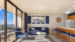 Ein modernes Wohnzimmer mit einer Couch, Sesseln, einem Couchtisch und einer Küchenzeile mit Barbereich.