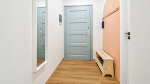 A hallway with a light blue door, a wooden bench, and a wall-mounted drying rack. - Enjoyable 1-bedroom apartment in charming Olomouc city center (Olomouc)