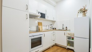 A modern kitchen with white cabinets, a microwave, a stove, and a refrigerator. - Enjoyable 1-bedroom apartment in charming Olomouc city center (Olomouc)