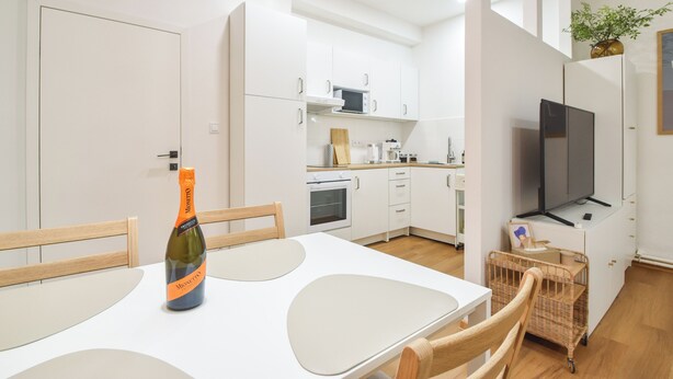 A modern kitchen with white cabinets, a microwave, and a television. - Enjoyable 1-bedroom apartment in charming Olomouc city center (Olomouc)