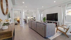 Ein modernes Wohnzimmer mit Sofa, Fernseher und Essbereich.
