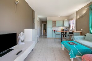 A modern hotel room with a flat-screen TV, a fan, a bed, a desk with a chair, and a kitchenette. - Callao Penthouse for Holidays with Balcony and Wi-Fi (Callao Salvaje)