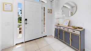 Una habitación con puerta blanca, un espejo, una cómoda con cajones y suelo de baldosas.