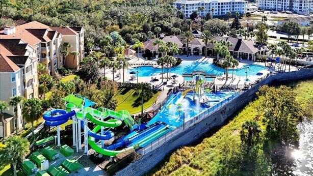 Un resort con una amplia piscina, toboganes acuáticos y vistas de edificios circundantes.