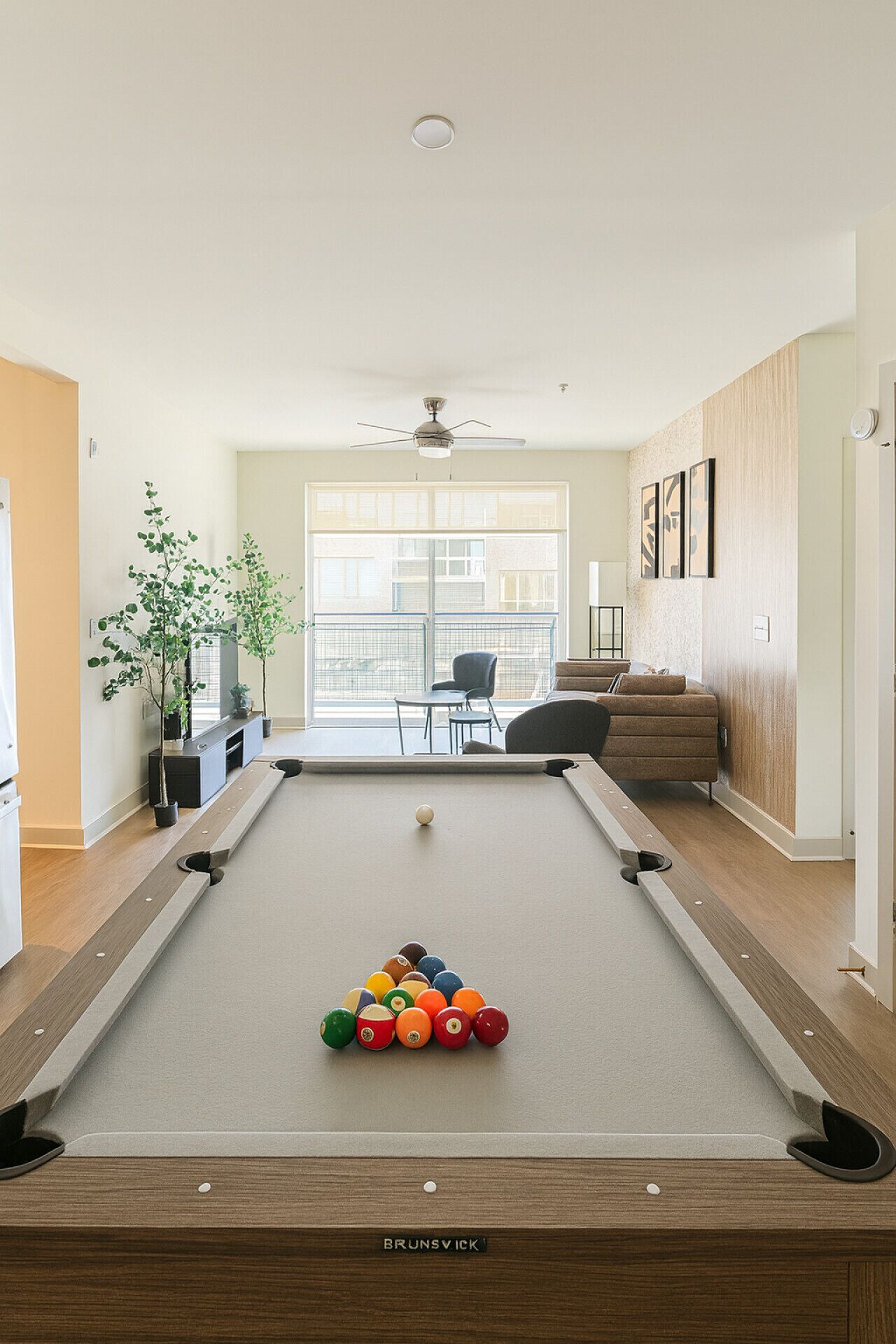 Une table de billard avec différentes sortes de billes, un ventilateur de plafond et une vue sur un balcon avec des sièges d’extérieur.