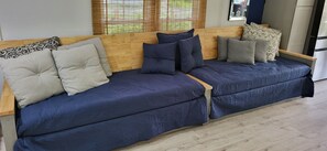 A sofa with patterned cushions, a wooden headboard, and a window with blinds. - Paws & Romance Riverside Dog Friendly Island Park,  Private back yard river (Albrightsville)