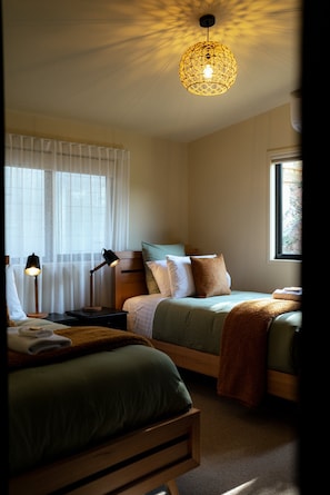 A bedroom with a bed, bedside tables, a lamp, a window, and a ceiling light fixture. - The perfect spot for family and friends (Bright)