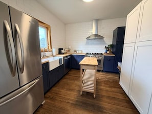 A modern kitchen with stainless steel appliances, wooden flooring, and a central island.