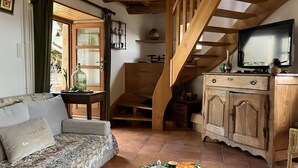 Ein Wohnzimmer mit einer Couch, einer Holztreppe, einem Fernseher und einem Tisch mit Tablett.