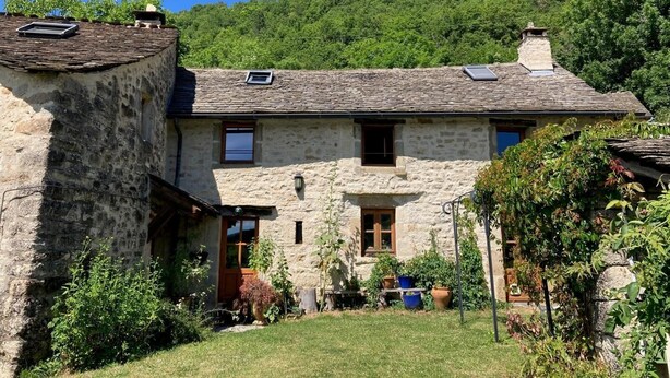 Ein Steinhaus mit geneigtem Dach, einer Haustür und einer kleinen Veranda.