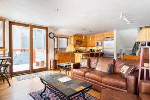 A spacious living area with a brown leather sofa, a coffee table, and a dining table. - Telluride Trails Retreat: 3BR/2BA - Hot Tub/Sauna (Telluride)
