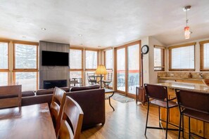 A modern living room with a fireplace, a TV, and a dining area with bar stools. - Telluride Trails Retreat: 3BR/2BA - Hot Tub/Sauna (Telluride)