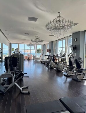 Ett gym med träningsutrustning, stora fönster och en kristallkrona.