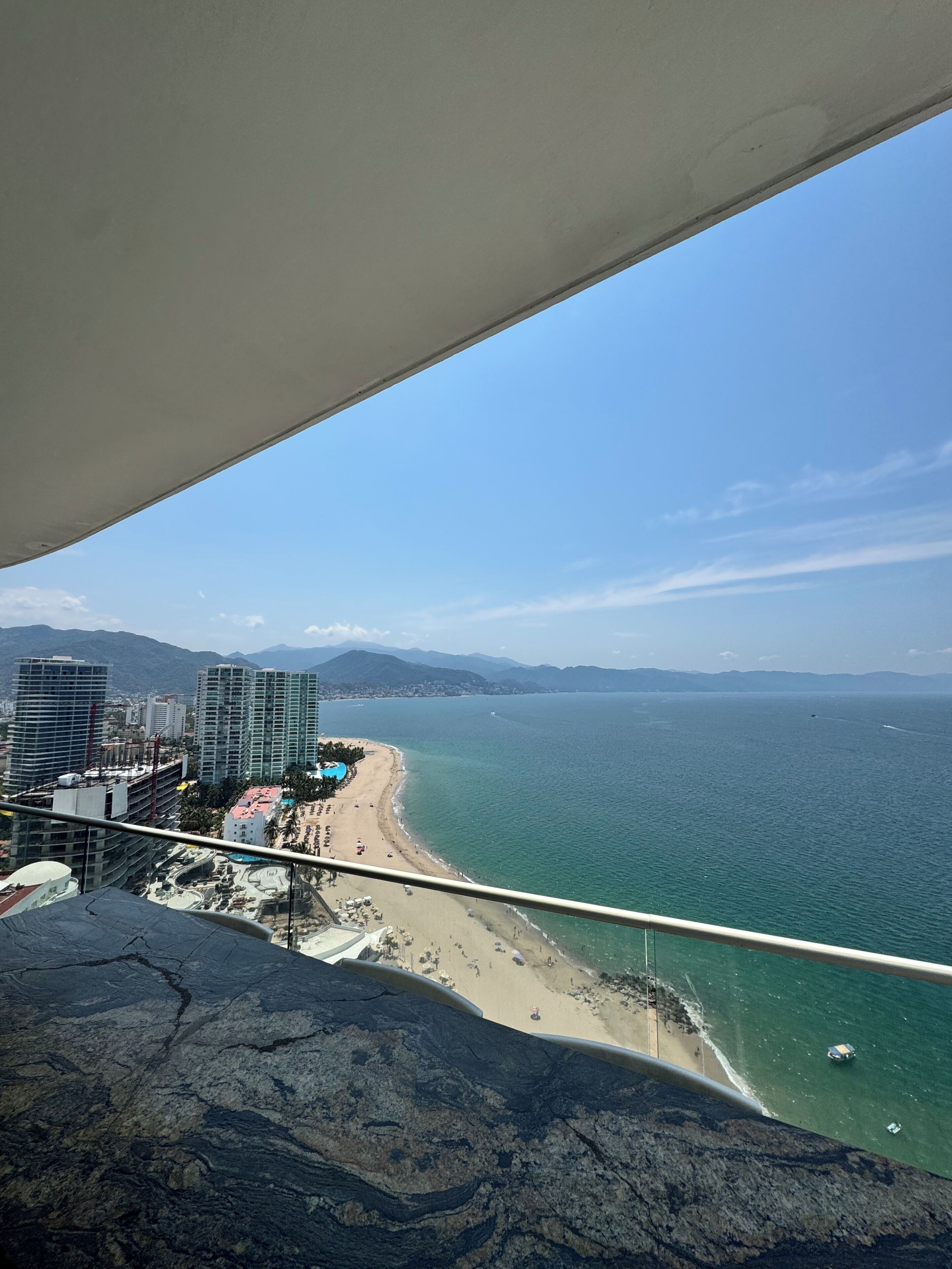 Un paisaje urbano costero con rascacielos, una playa y un cielo despejado.