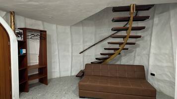 A room with a brown sofa, a wooden ladder-like structure, and a tiled floor.
