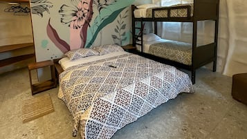 A bunk bed with a patterned bedspread, a wall with a floral mural, and a small wooden table.