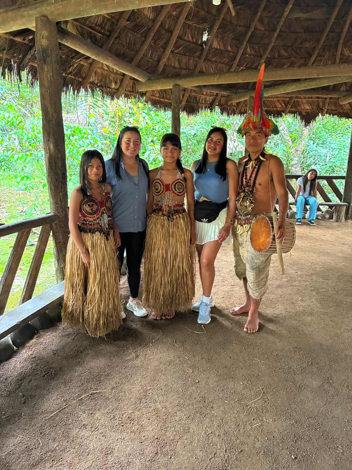 Un grupo de personas vestidas con atuendo tradicional bajo una estructura de techo de paja.