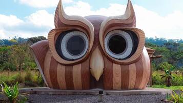 Una gran escultura de madera de un búho con un camino de grava delante.