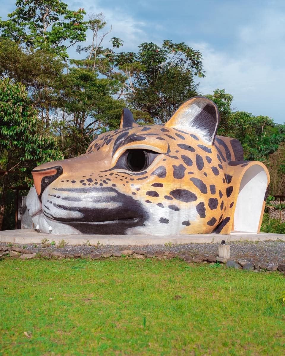 A large sculpture of a jaguar's head in an outdoor setting.