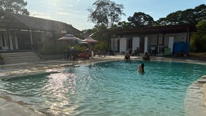 A swimming pool with clear water, surrounded by a covered area with steps leading up to it. - Animal Glamping (Pomona)