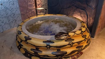 A hot tub with a snake design, surrounded by stone walls and a small table.