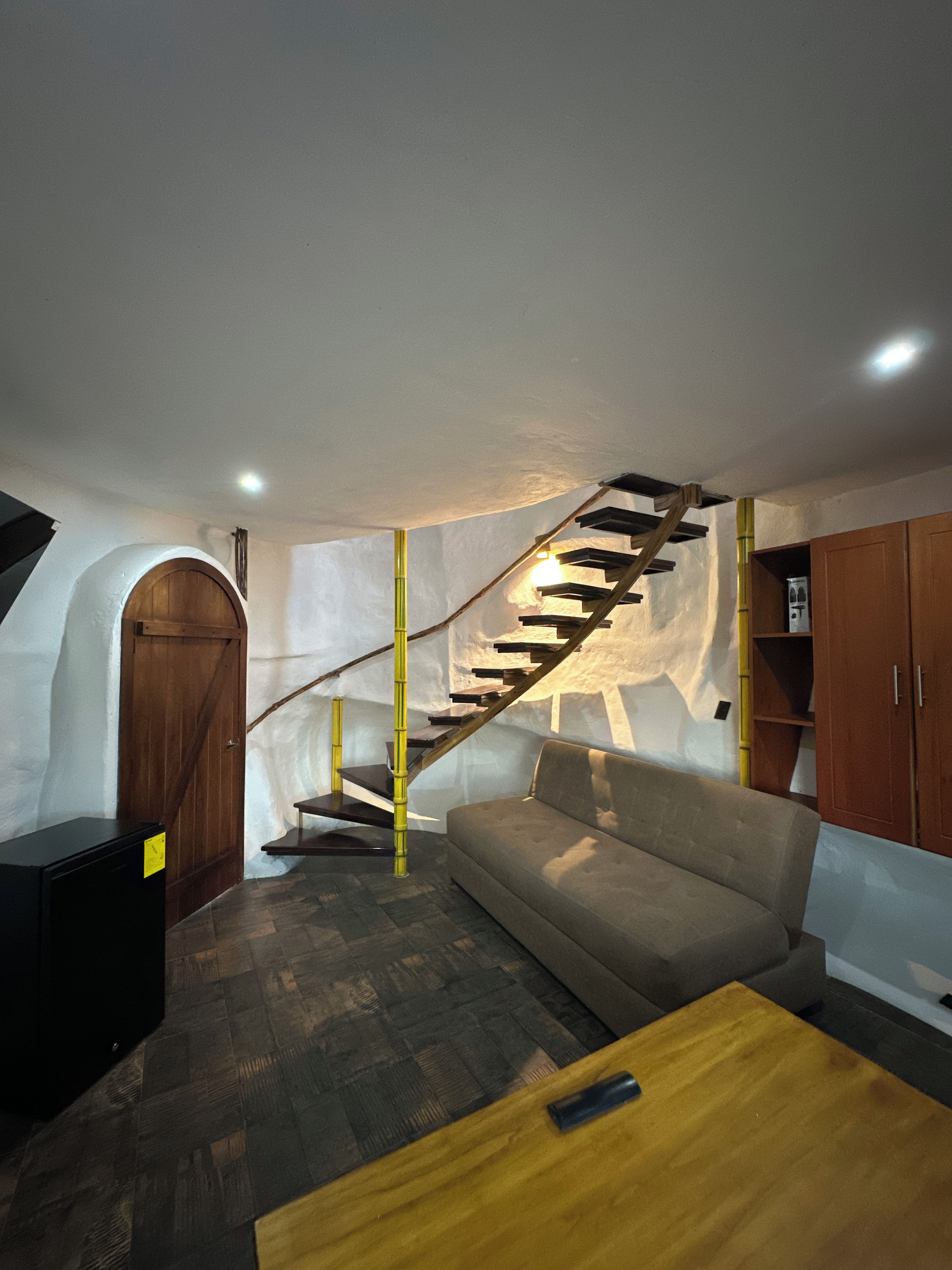 Un interior moderno con una escalera de madera, un sofá y una mesa de madera.
