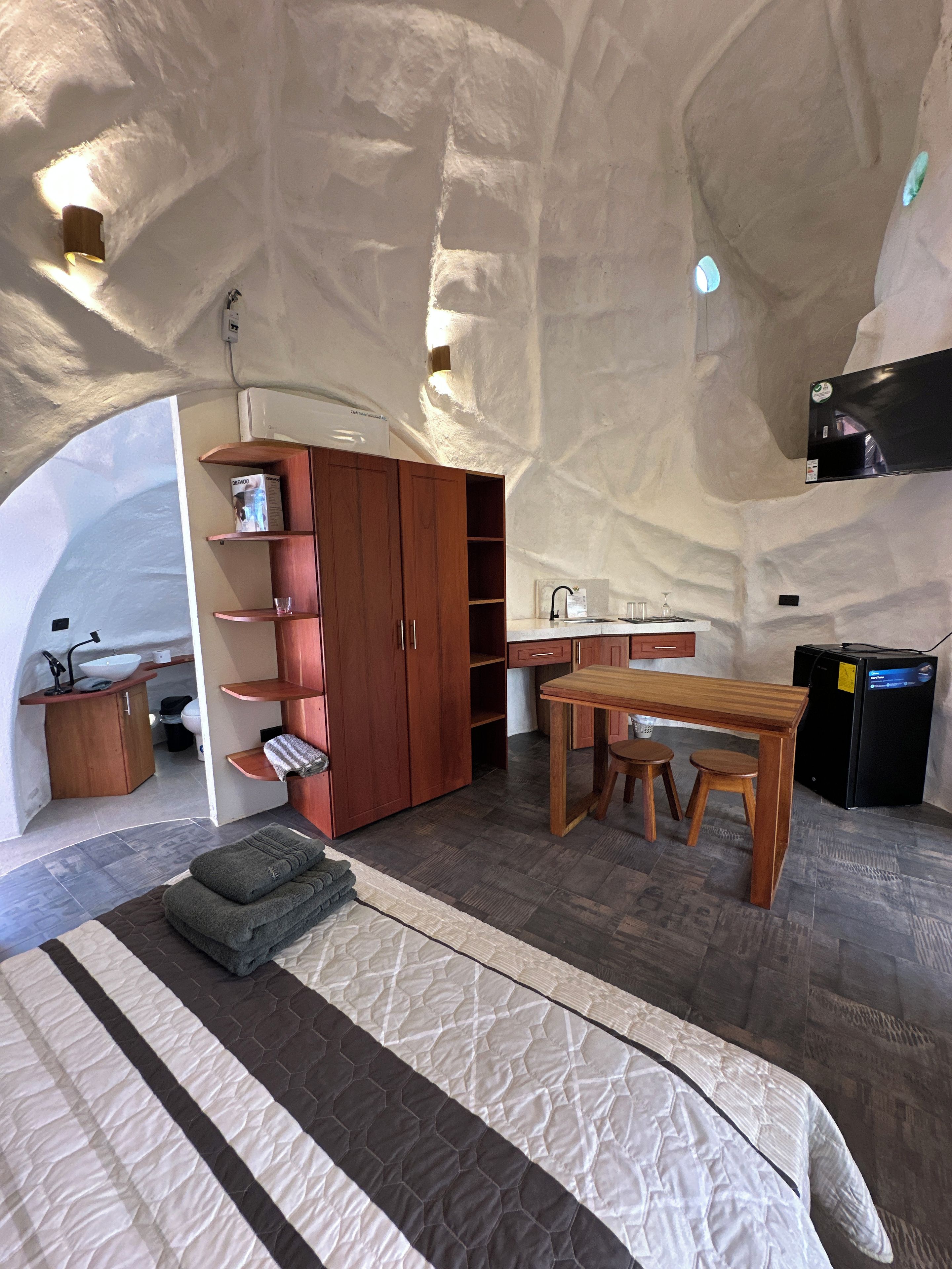 Un interior moderno y compacto con cama, kitchenette y comedor.