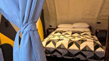 A room with a bed, a nightstand, and a curtain.