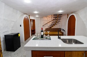 Una cocina con encimera blanca, refrigerador negro y escalera de madera.