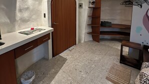 A compact, modern kitchen with a wooden door, built-in shelves, and a small dining area. - Animal Glamping (Pomona)
