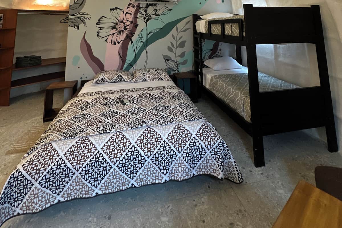 A bunk bed room with a floral mural, a patterned bedspread, and a wooden chair.