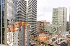 A high-rise urban area with modern architecture, including a prominent building with a glass facade and a red-brick structure with a unique roof design. - Modern 2BDR in Canary Wharf with Balcony Views (Greater London)