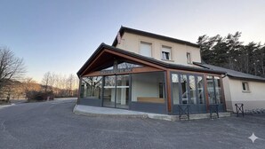 A restaurant with a modern design, large windows, and a covered outdoor seating area. - Gîte du Roc 8/10 persons (SAINT-SAUVEUR-DE-PEYRE)