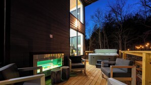 Een terras buiten met houten vloer, een hottub en zitgedeeltes.